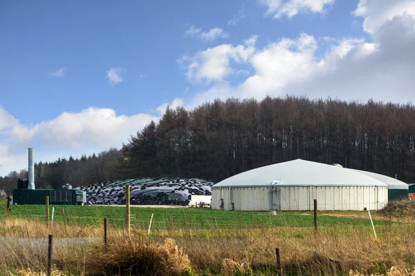 Planta de biogás para energías renovables entre campo y bosque, cielo azul con nubes —  Fotos de Stock