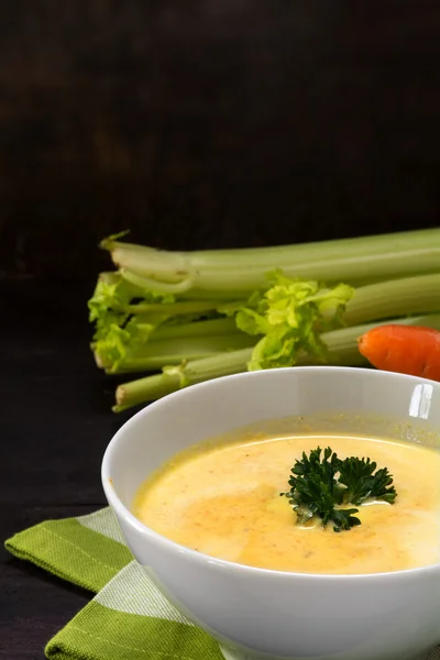 Soupe à la crème de légumes avec garniture de céleri et persil, fond en bois foncé avec espace de copie, verticale — Photo