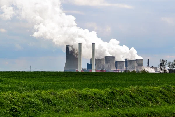 Brunkol gaseldade kraftverk bakom en jordbruksområdet landscap — Stockfoto