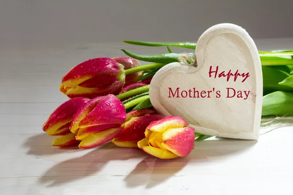 Fresh red orange tulips and a wooden heart, love decoration text happy mother's day — Stock Photo, Image