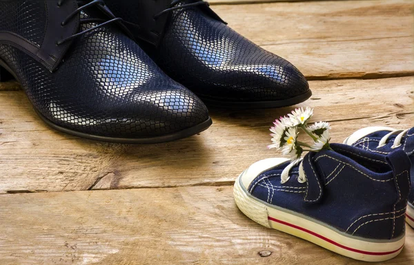 Happy fathers day, small kids sneakers with a bouquet of daisies and daddy's black shoes — Stock Photo, Image