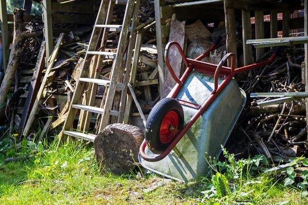 独轮车靠头顶上的小屋凌乱堆积木材 — 图库照片