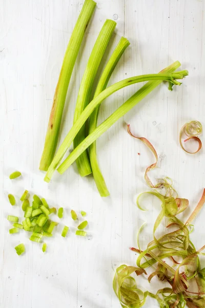 Rhubarb stalks, slices and spirals from the peel on white wood, from above — Stock Photo, Image