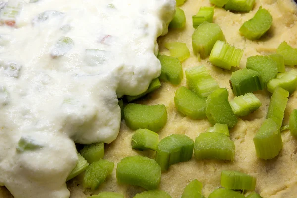 Facendo torta di rabarbaro, fette di rabarbaro sulla pasta frolla cruda e una copertura di meringa, primo piano — Foto Stock