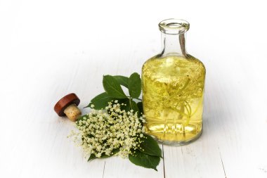 Beyaz ahşap bir masa syr üzerinde cam şişede elderflower içki
