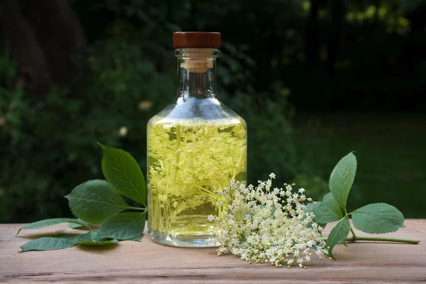 Bebida caseira de sabugueiro em uma garrafa de vidro em uma mesa de madeira no jardim — Fotografia de Stock