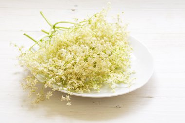 Beyaz ahşap zemin üzerinde bir tabakta elderflowers