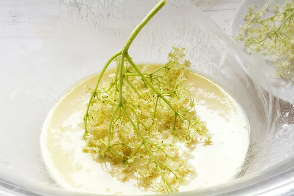 Flor de saúco sumergido en un tazón de vidrio con masa de panqueque para hornear un postre tradicional fino — Foto de Stock