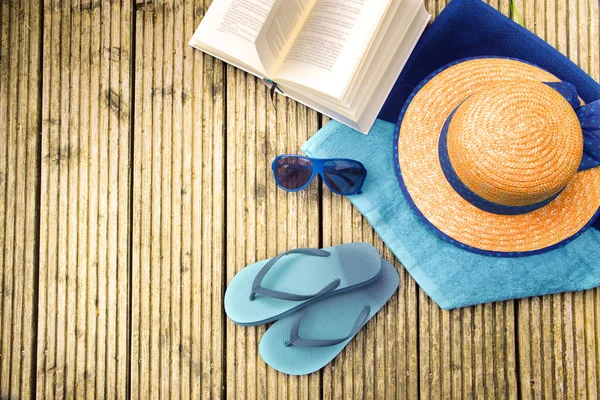 Vacaciones de verano, sombrero de paja, chanclas, gafas de sol azules, toallas turquesa y un libro sobre una pasarela de madera, vista desde arriba —  Fotos de Stock