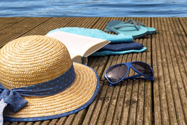 Vacaciones de verano, accesorios para vacaciones de playa en un embarcadero de madera justo en el agua —  Fotos de Stock