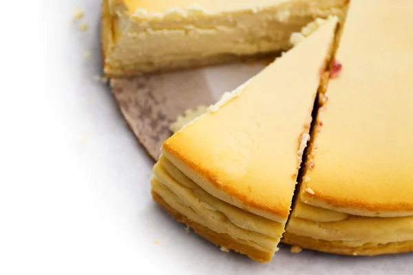 Cheesecake caseiro com uma peça em fatias, fundo desbota para branco — Fotografia de Stock