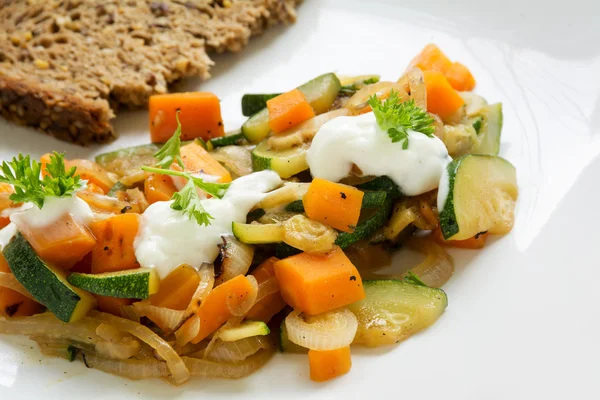 Verduras de verano de calabacín y zanahorias con crema agria, guarnición de perejil y pan integral, primer plano —  Fotos de Stock