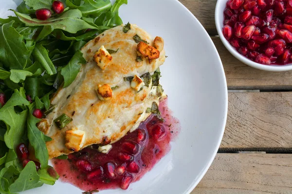 Fried chicken breast fillet gratinated with feta cheese, arugula salad and pomegranate sauce — Stock Photo, Image