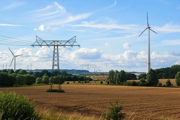 wind turbines and electricity pylons in a rural landscape against a blue sky, renewable energy concept