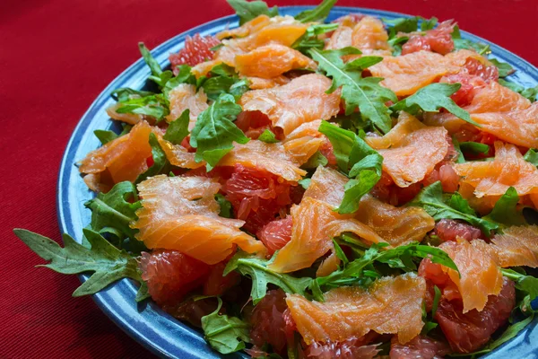 Sallad med rucola, grapefrukt och lax på en röd bordsduk — Stockfoto