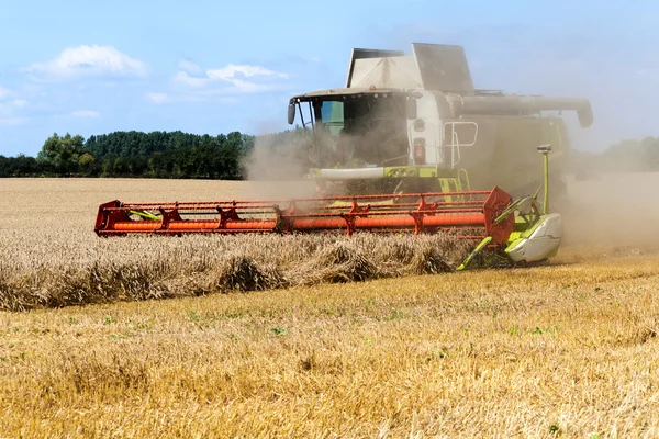 Combineren van oogstmachine werkt met stof op het veld in een landelijke omgeving — Stockfoto