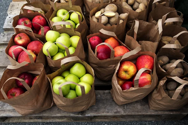 Sacos de papel com maçãs e batatas biológicas no mercado — Fotografia de Stock