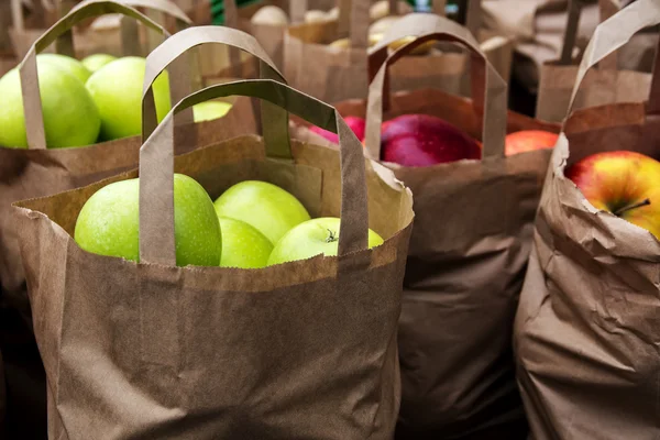 Papperspåsar med ekologiska gröna och röda äpplen på marknaden — Stockfoto