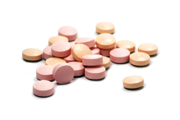 Píldoras de color rosa en un pequeño montón aislado con sombras en blanco — Foto de Stock