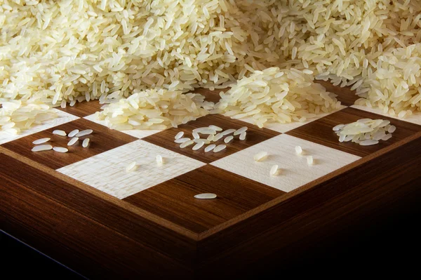 Tablero de ajedrez con crecientes montones de granos de arroz, leyenda sobre el crecimiento exponencial — Foto de Stock