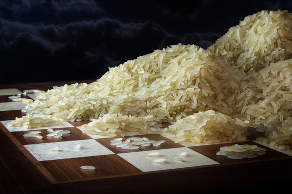 Tabuleiro de xadrez com montes crescentes de grãos de arroz, conceito de crescimento exponencial — Fotografia de Stock