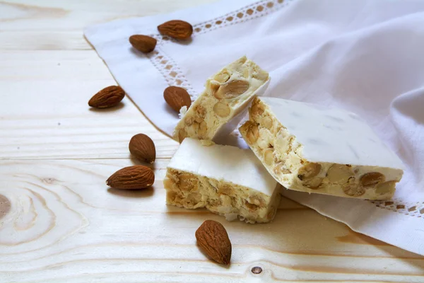 Torrone or white nougat with almonds and napkin on a wooden table — Stock Photo, Image