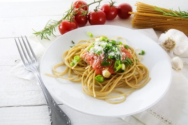 Seluruh pasta spageti gandum dengan saus tomat segar dan bawang pada kayu pedesaan putih — Stok Foto