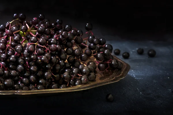 흑인 elderberries 무리 (Sambucus nigra) 어두운 배경으로 소박한 나무 테이블에 오래 된 실버 접시에 — 스톡 사진