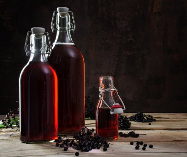 Kırmızı suyuyla şişe rustik ormanda, koyu arka plan üzerinde siyah elderberries (Sambucus nigra)