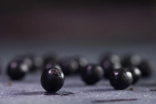 Algunas bayas de saúco en un plato de pizarra azul-gris, fondo borroso — Foto de Stock