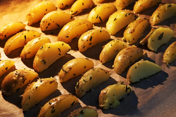 Aardappel partjes met rozemarijn op papier in de hete oven bakken — Stockfoto