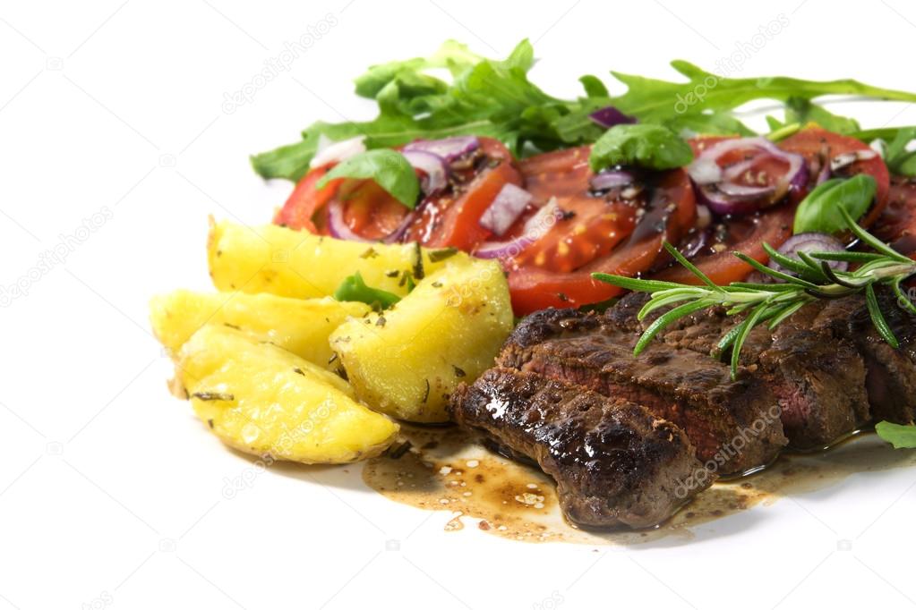 roasted beef filet mignon with potatoes and tomato arugula salad isolated on a white background