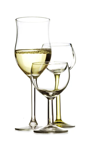 Three drinking glasses, one is filled with white wine, the others are empty, isolated on a white — Stock Photo, Image