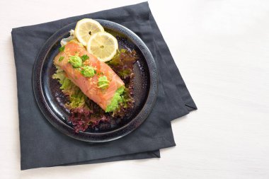 Limon dilimleri ve maydanoz garnitürlü bezelye püresi ile bezelye püresi dolu füme somon, beyaz bir masa üzerinde koyu tabak ve peçete, fotokopi alanı, yukarıdan yüksek açılı görüş.