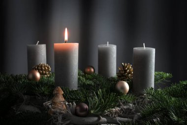 Dört mum, biri köknar dalları ve Noel süslemelerinden gelen bir düzenleme üzerine aydınlatılmış. Fotokopi alanı ile koyu gri bir arkaplan üzerine tatil süslemesi. Seçilmiş odak, dar alan derinliği.
