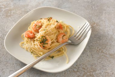 Karides, sarımsak ve bitkilerle aperatif spagetti, küçük bir tabakta Akdeniz mahsulü, kopyalanmış gri arka plan, seçilmiş odak, dar alan derinliği.