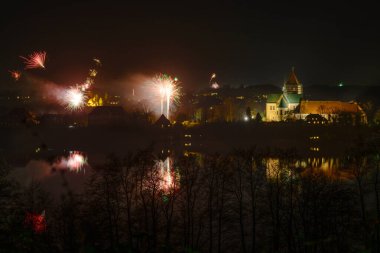 Ratzeburg Katedrali 'nde yeni yıl havai fişekleri. Geceleri gölde yansımalar, karanlık gökyüzünde fotokopi.