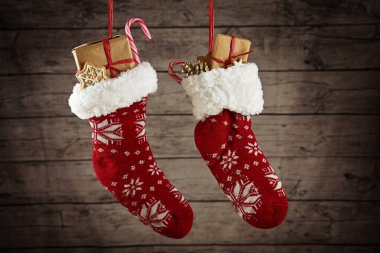 Hediyeler ve şekerlerle dolu bir çift Noel çorabı kırsal bir ahşap duvarın önünde asılı, seçilmiş odak noktası