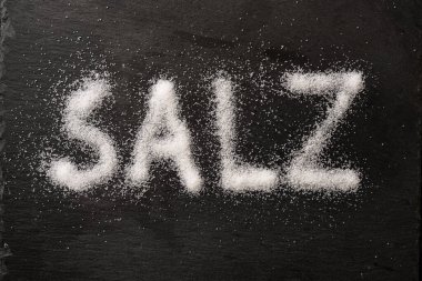 Almanca Salz (anlamı tuz), yukarıdan seçilmiş, yukarıdan yüksek açı görünümlü, koyu bir levha üzerinde tuz kristalleri ile yazılmış