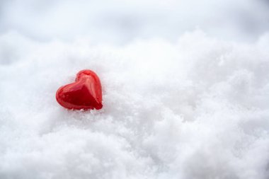 Beyaz karda yatan küçük kırmızı kalp, sevgililer günü için sevgi sembolü cömert kopya alanı, seçilmiş odak, dar alan derinliği
