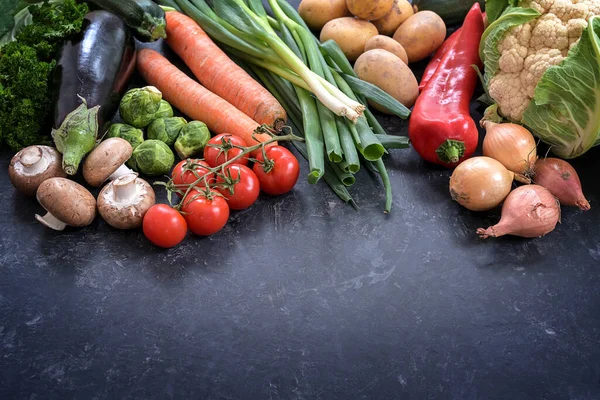 Various vegetables on a dark gray slate background, healthy food concept for fitness and lose weight diet, copy space, selected focus