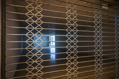 Coronavirus salgını sırasında perakende kilitleme, kopyalama alanı, seçili odak, dar alan derinliği nedeniyle bir alışveriş merkezindeki boş bir mağazanın önündeki metalden kapalı koruyucu kaplama ızgarası, ekonomik kriz ve iflas