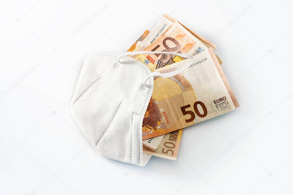 ffp2 medical protection face mask against coronavirus filled with euro banknotes, concept for rising costs in health care or enrichment by corruption, white background with copy space