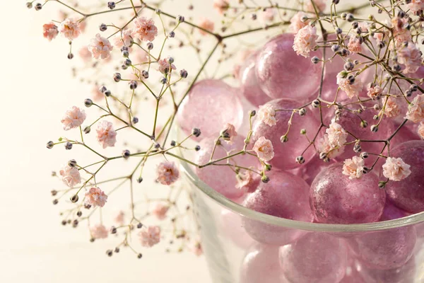 pink glass marbles and blush gypsophila flowers as a feminine decoration for beauty, wellness and romantic interior concepts, copy space, selected focus, narrow depth of field