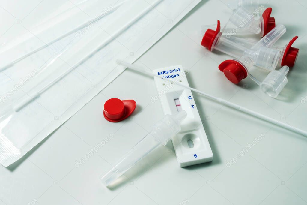 Rapid antigen test for COVID-19 diagnostic at home, self-test kit with nasal swabs, tubes and detection device on a light turquoise background, copy space, selected focus, narrow depth of field