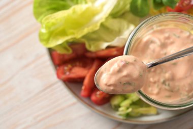 Bir kaşıkta gökyüzüne ve cam kavanoza dayalı Bin Ada sosu dilimlenmiş marul ve domates salatası, sağlıklı çiğ yemek, seçilmiş odak, çok dar bir tarla derinliği