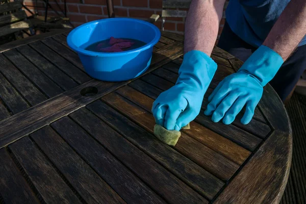 Man Blue Rubber Gloves Cleaning Dark Wooden Garden Table Beginning — Stok fotoğraf