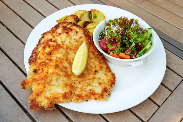 Wiener Schnitzel Met Citroenschijfje Salade Gebakken Aardappel Een Houten Tuintafel — Stockfoto
