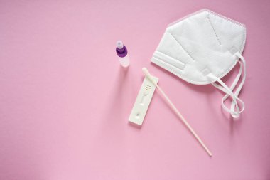 Covid-19 hızlı test, burun değişimi, sıvı şişe ve pembe arka planda tıbbi ffp2 yüz maskesi, Coronavirus salgını sırasında sağlık konsepti, fotokopi alanı, yukarıdan yüksek açı görünümü, seçilmiş odak noktası