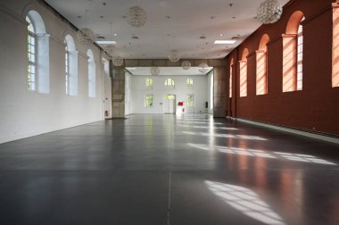 Putbus, Almanya, 22 Ağustos 2021: Rugen adasındaki Putbus Marstall 'ın içinde yüksek kemerli pencereleri olan büyük boş salon, mimari ve iç mekan konsepti, gri katta kopyalama alanı, seçili odak noktası